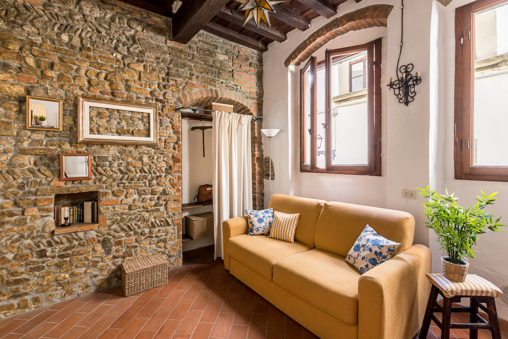 На фото: маленькая открытая гостиная комната в средиземноморском стиле с разноцветными стенами, полом из терракотовой плитки и оранжевым полом для на участке и в саду