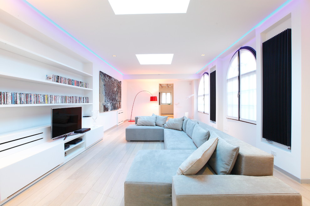 Offenes, Großes Modernes Wohnzimmer mit weißer Wandfarbe, hellem Holzboden und freistehendem TV in Mailand