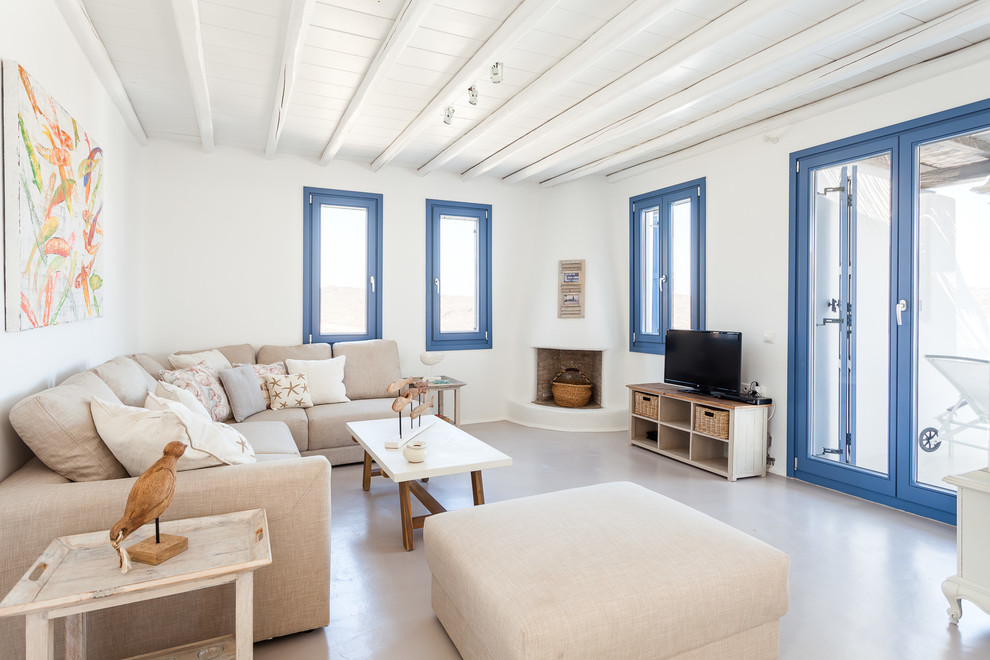 Offenes Maritimes Wohnzimmer mit weißer Wandfarbe, Eckkamin, Kaminumrandung aus Backstein und freistehendem TV in Sonstige