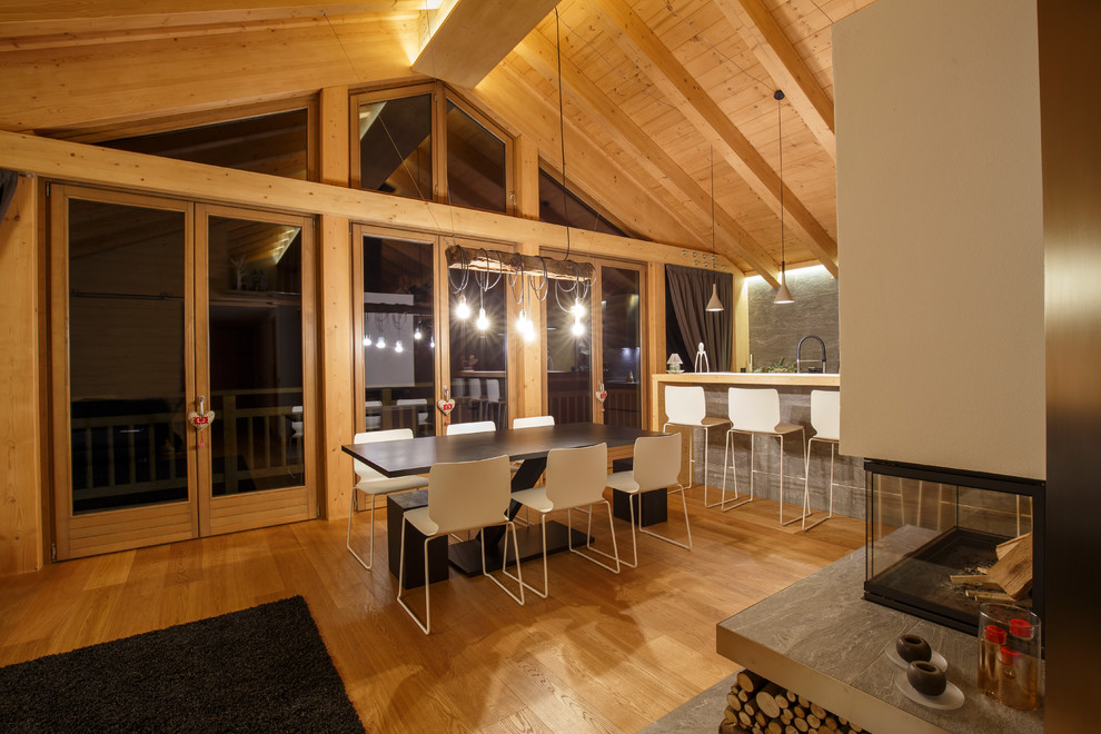 Exemple d'un grand salon montagne ouvert avec une salle de réception, un mur gris, un sol en bois brun, une cheminée double-face, un manteau de cheminée en carrelage, un téléviseur dissimulé et un sol marron.