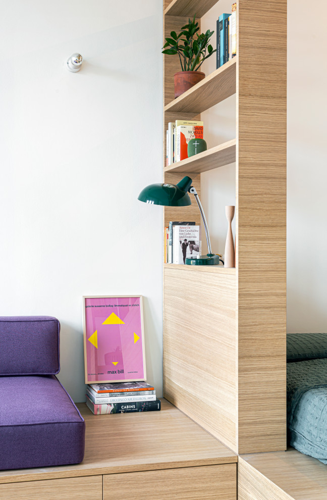 Esempio di un piccolo soggiorno design aperto con libreria, pareti bianche, pavimento in legno massello medio e nessuna TV