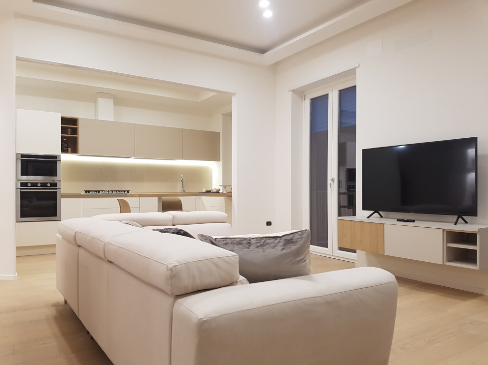 Diseño de sala de estar abierta moderna de tamaño medio con paredes blancas y suelo de madera clara