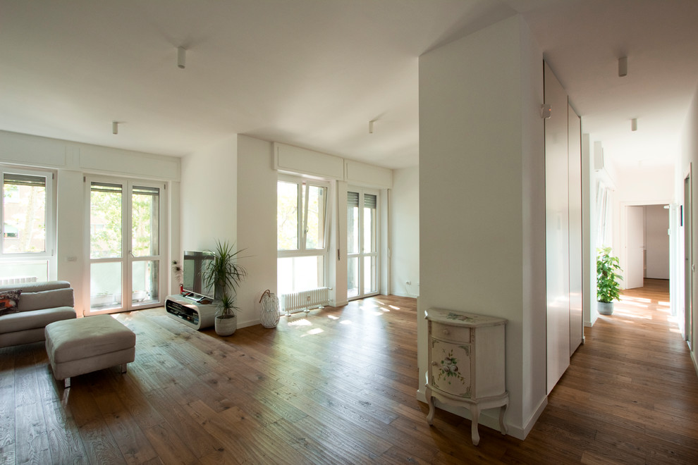 Cette image montre un grand salon design ouvert avec un mur blanc et parquet clair.