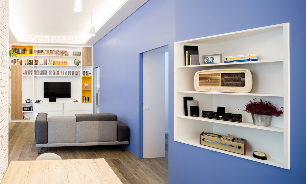 Imagen de biblioteca en casa abierta contemporánea pequeña con paredes azules, suelo de baldosas de porcelana, televisor colgado en la pared y suelo marrón