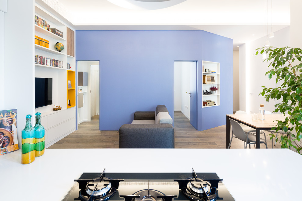 Imagen de biblioteca en casa abierta actual pequeña con paredes azules, suelo de baldosas de porcelana, televisor colgado en la pared y suelo marrón