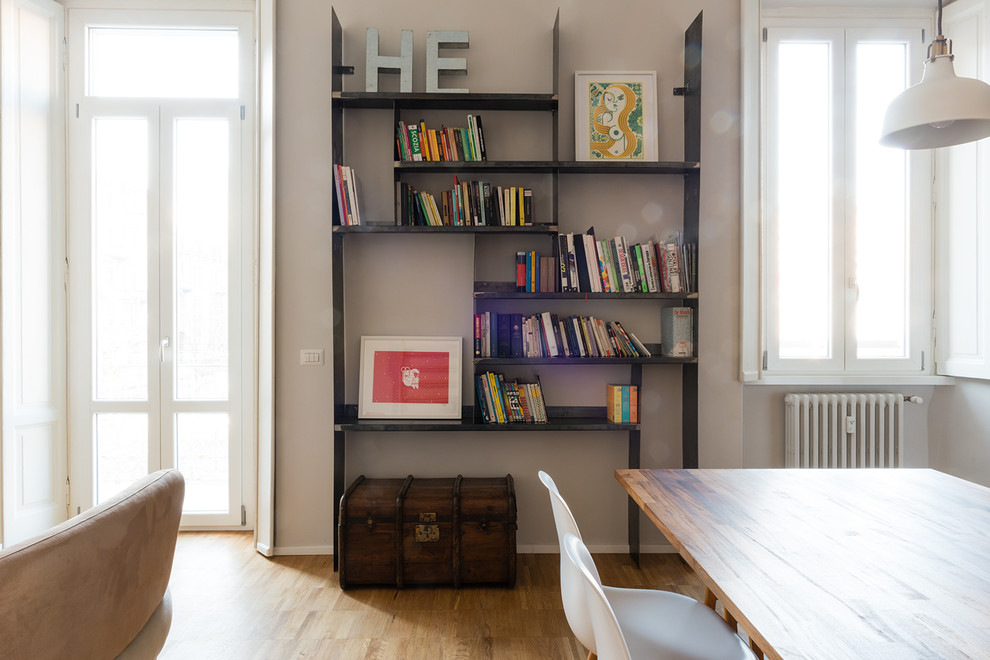 Esempio di un soggiorno design di medie dimensioni e stile loft con libreria, pareti grigie e parquet chiaro