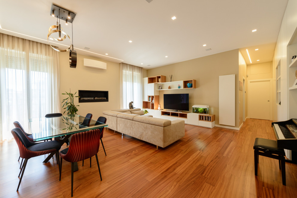 Modelo de salón abierto actual grande con paredes beige, suelo de madera clara y suelo marrón