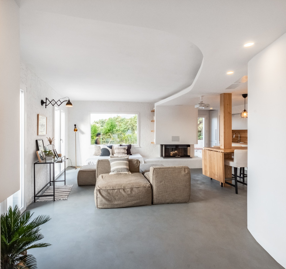 Mid-sized beach style open concept concrete floor and gray floor living room photo in Other with white walls, a corner fireplace and a plaster fireplace