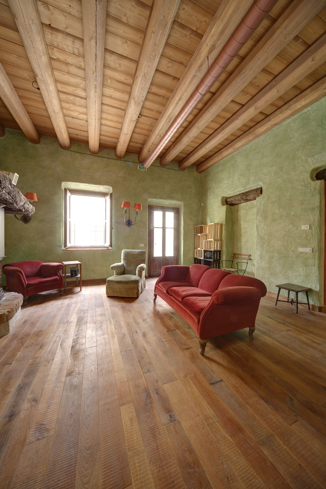 Ejemplo de salón abierto campestre extra grande con paredes verdes, suelo de madera en tonos medios y marco de chimenea de madera