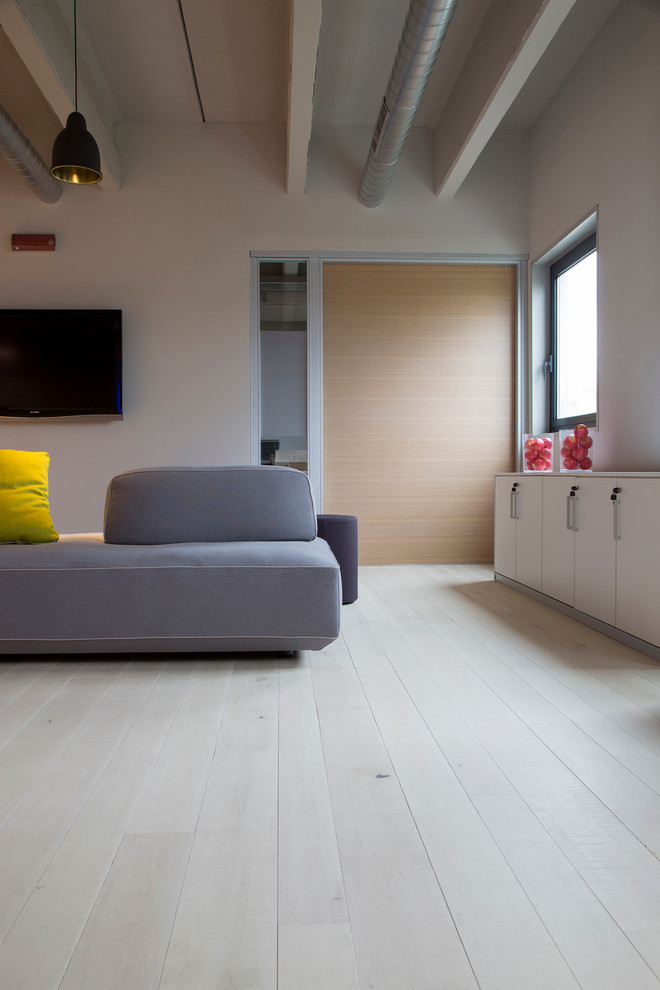 Esempio di un grande soggiorno design aperto con pareti bianche, parquet chiaro e TV a parete