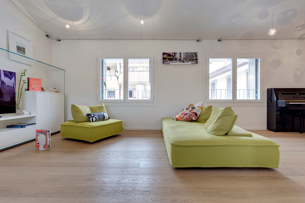 Imagen de salón abierto actual grande con paredes blancas, suelo de madera en tonos medios y televisor colgado en la pared