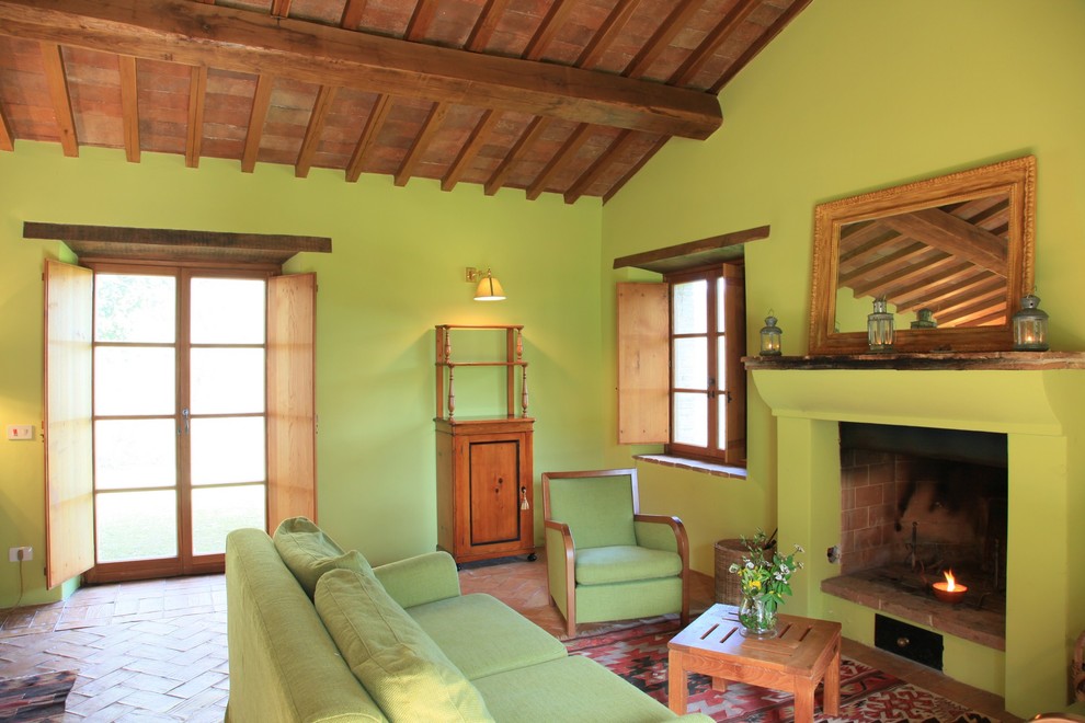 Réalisation d'un salon méditerranéen ouvert avec un mur vert, tomettes au sol, une cheminée standard, un manteau de cheminée en plâtre et aucun téléviseur.
