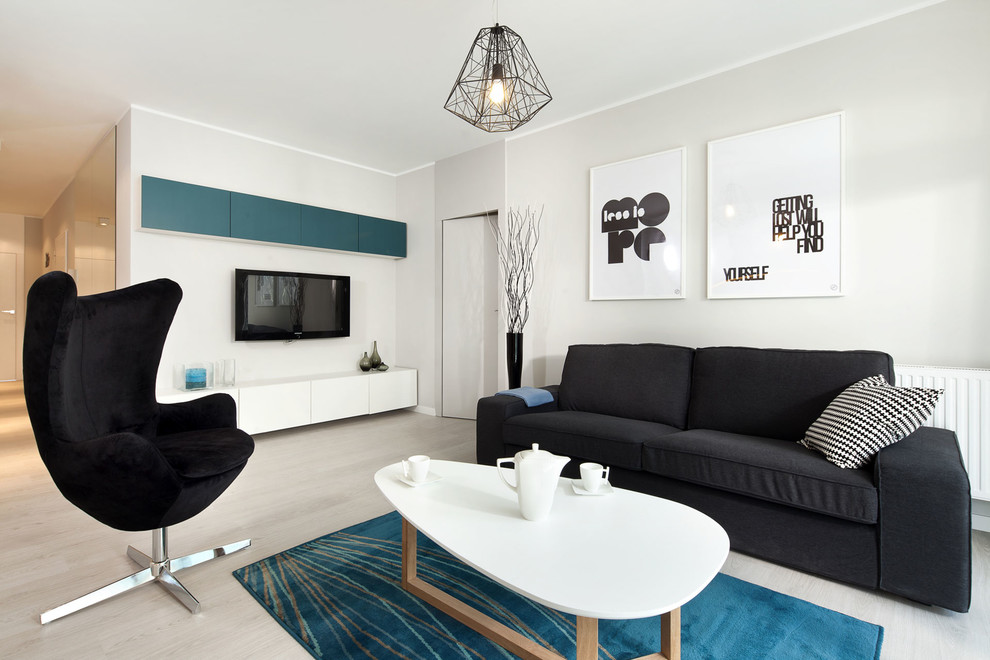 Diseño de salón abierto moderno de tamaño medio con paredes grises, suelo de madera clara, televisor colgado en la pared y suelo gris