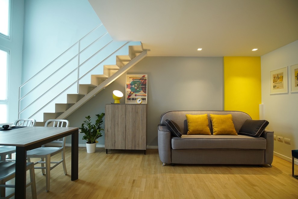 Example of a trendy open concept light wood floor and beige floor living room design in Milan with multicolored walls and no fireplace