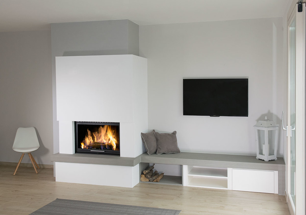 Стильный дизайн: изолированная гостиная комната среднего размера в скандинавском стиле с серыми стенами, светлым паркетным полом, угловым камином, фасадом камина из камня и телевизором на стене - последний тренд