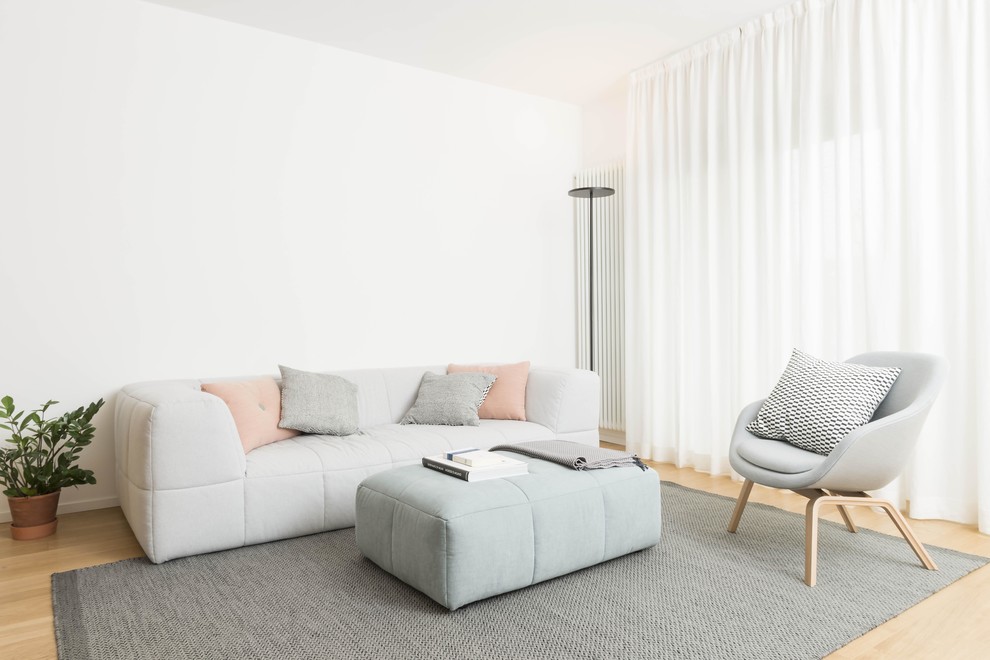Modelo de salón para visitas nórdico con paredes blancas, suelo de madera clara, suelo beige y alfombra