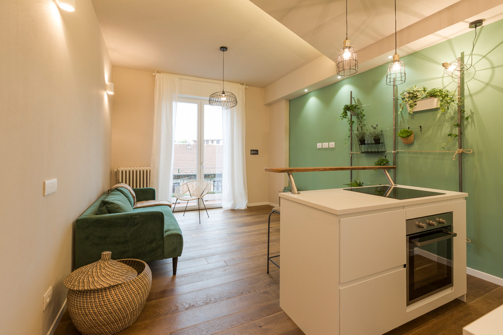 Mittelgroßes Wohnzimmer mit grüner Wandfarbe, hellem Holzboden und braunem Boden in Mailand
