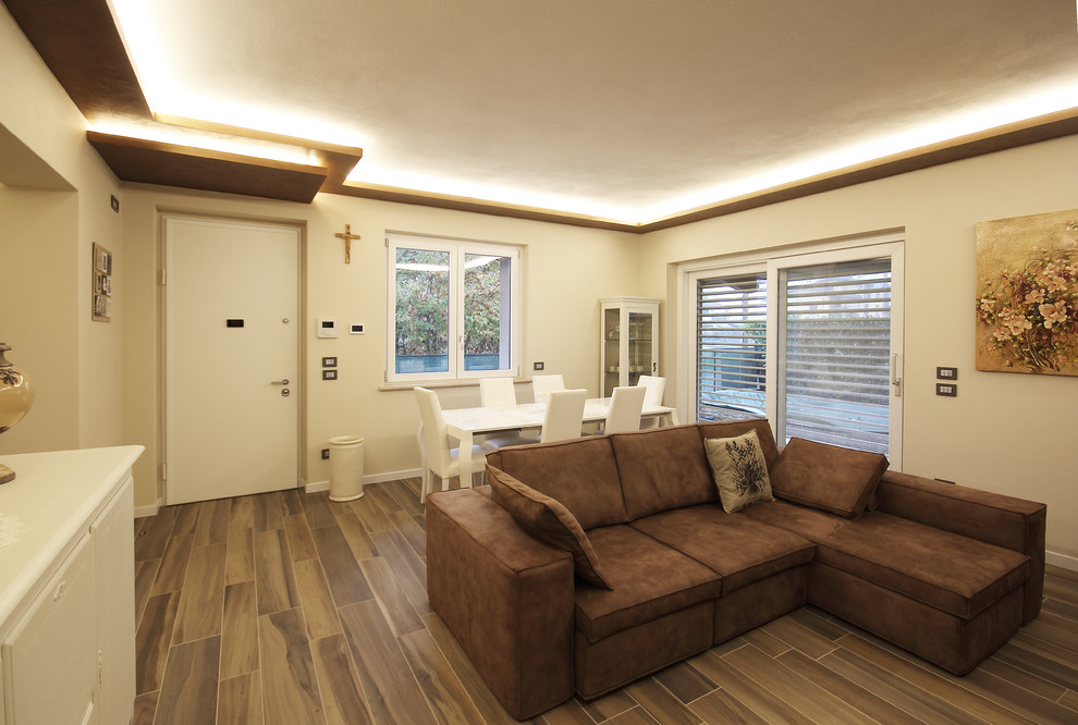 Modelo de salón abierto contemporáneo de tamaño medio con paredes beige, suelo de baldosas de cerámica, marco de chimenea de metal y suelo marrón