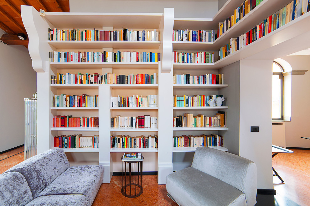 Esempio di un soggiorno mediterraneo con libreria, pareti bianche e pavimento marrone