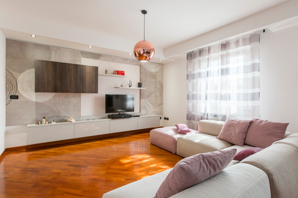 Ejemplo de salón abierto actual de tamaño medio con suelo de madera en tonos medios, paredes blancas y televisor colgado en la pared
