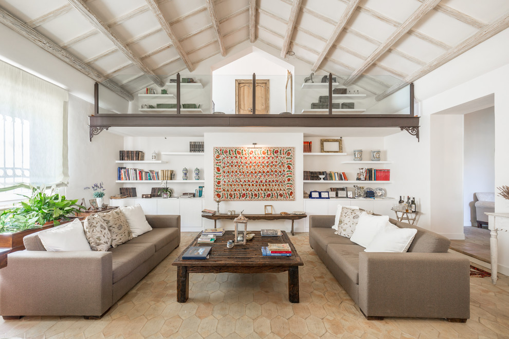 Esempio di un grande soggiorno mediterraneo aperto con libreria, pareti bianche, pavimento in terracotta e nessuna TV
