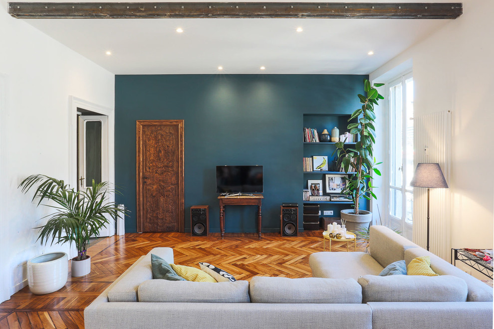 Réalisation d'une salle de séjour design de taille moyenne et fermée avec une salle de musique, un mur bleu, un sol en bois brun, aucune cheminée, un téléviseur encastré et un sol marron.