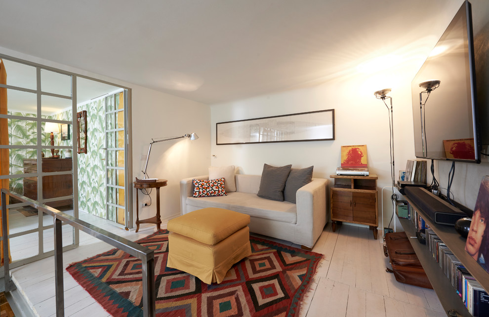 Foto de sala de estar tipo loft mediterránea pequeña sin chimenea con paredes blancas, suelo de madera pintada, televisor colgado en la pared, suelo blanco y alfombra