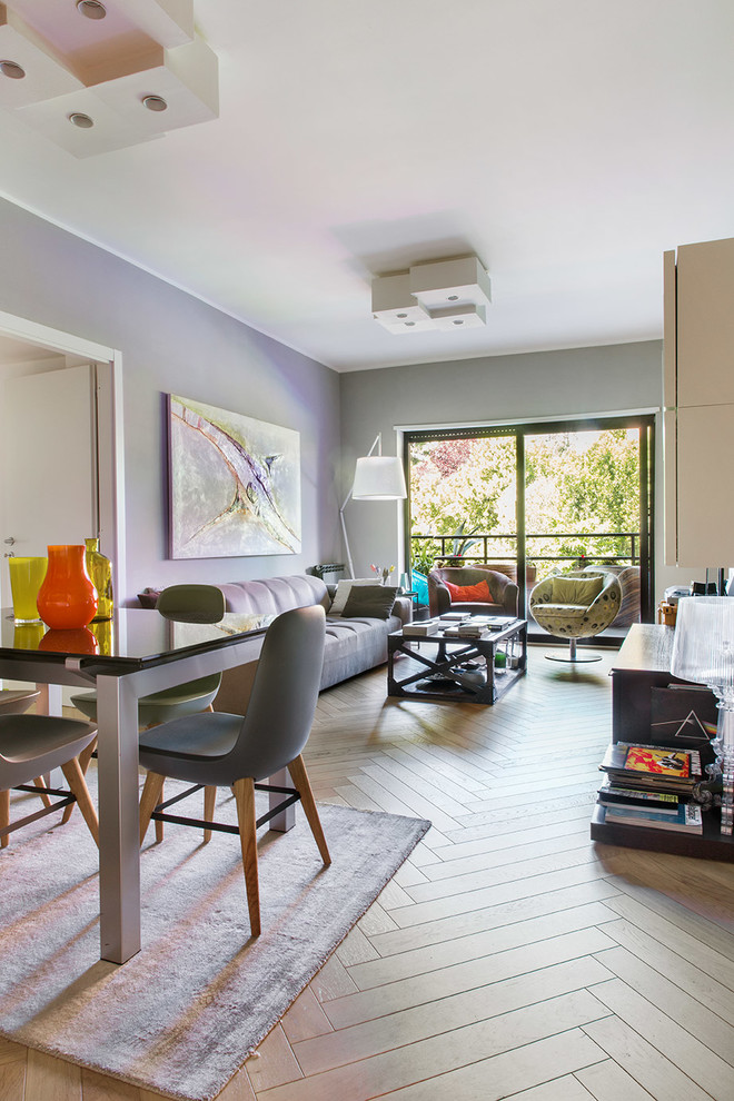 Immagine di un soggiorno design di medie dimensioni e chiuso con pareti grigie, parquet chiaro, parete attrezzata e pavimento beige