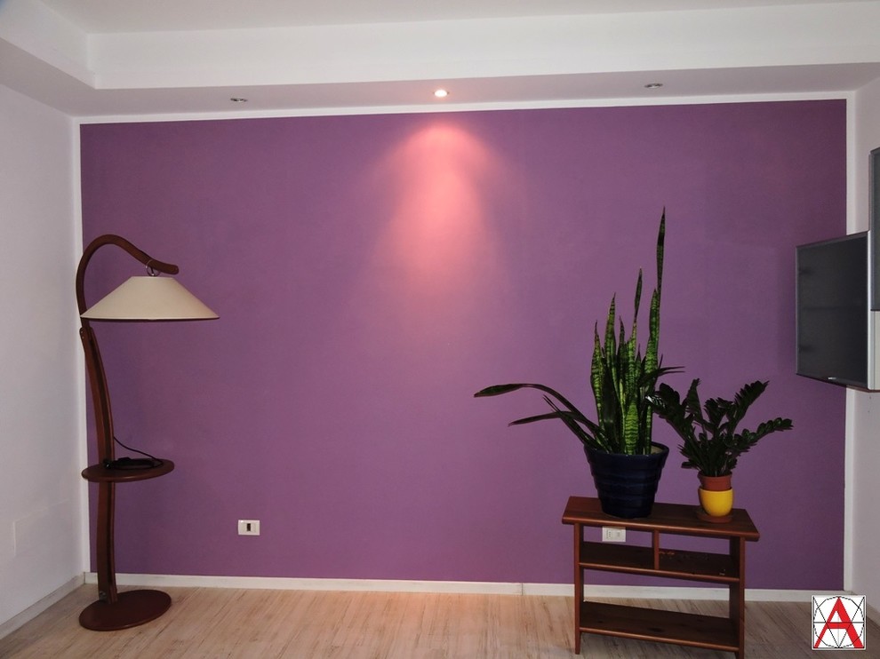 Aménagement d'un salon moderne ouvert avec un mur violet et parquet clair.