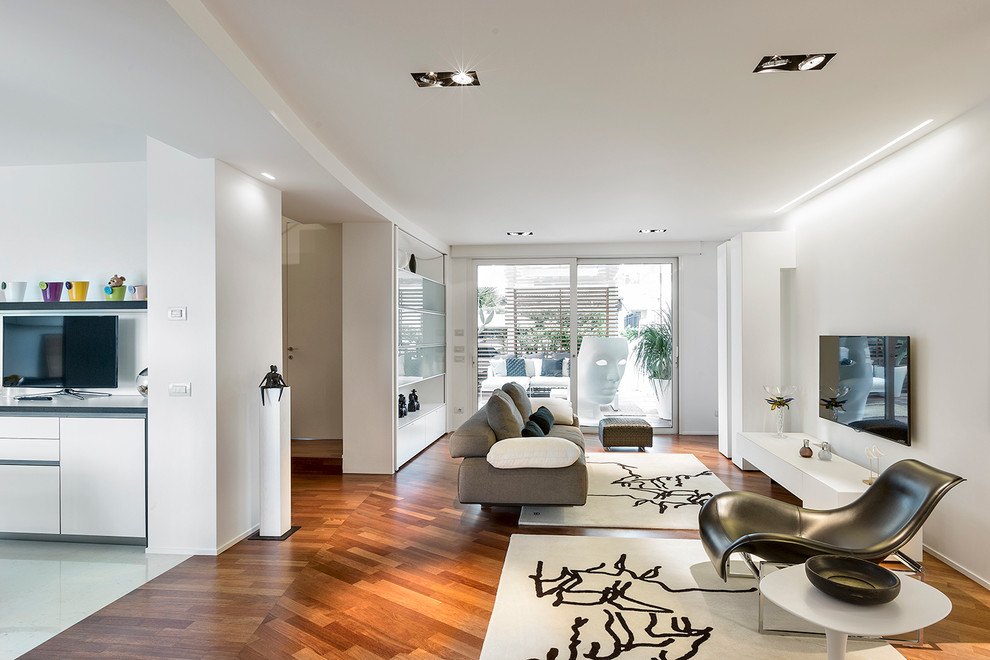 Aménagement d'un grand salon contemporain ouvert avec un sol en bois brun, un téléviseur fixé au mur et un mur blanc.