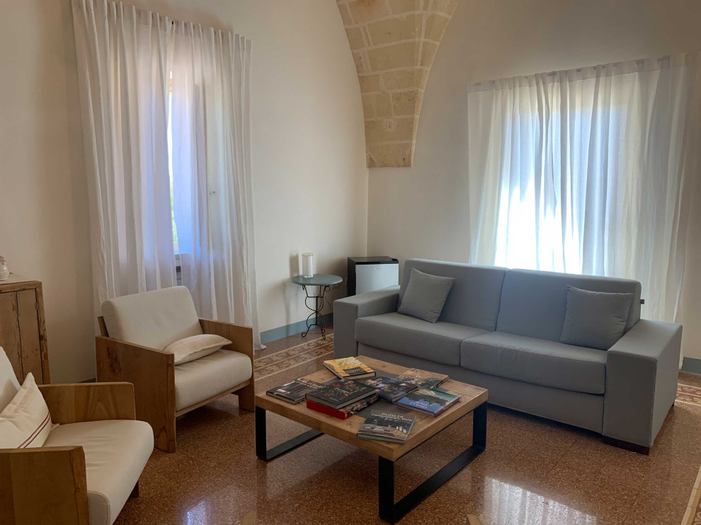 Пример оригинального дизайна: изолированная гостиная комната в средиземноморском стиле с белыми стенами, бетонным полом, сводчатым потолком и разноцветным полом