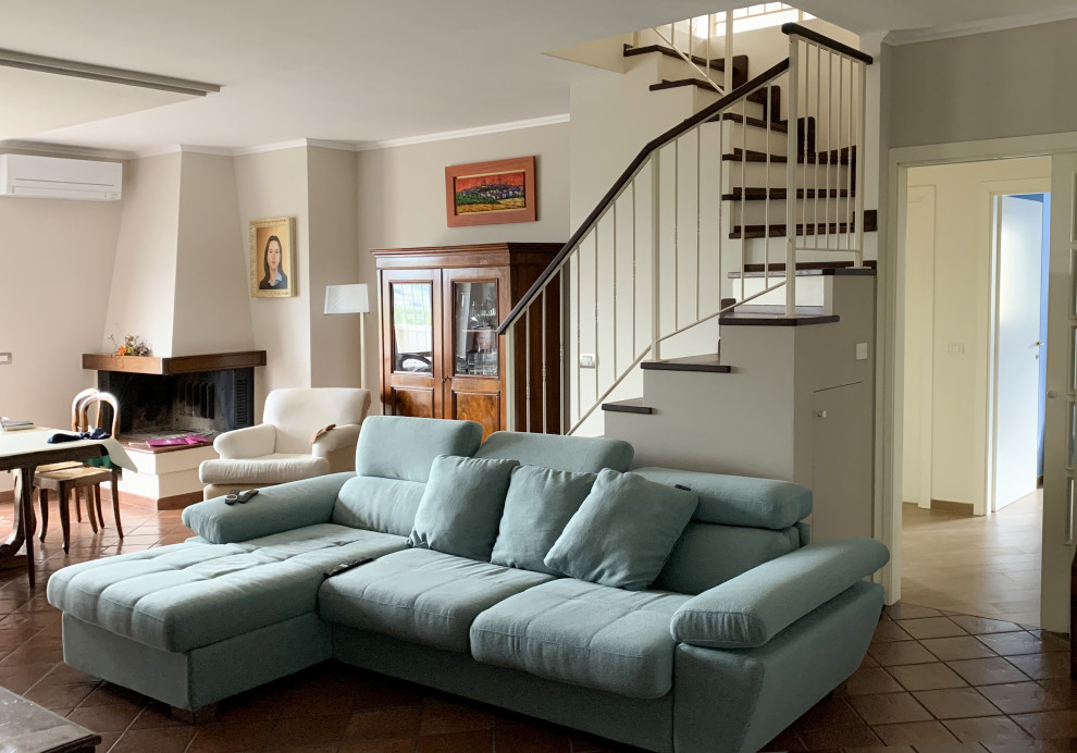 Esempio di un grande soggiorno shabby-chic style aperto con libreria, pareti beige, pavimento in terracotta, camino ad angolo e TV a parete
