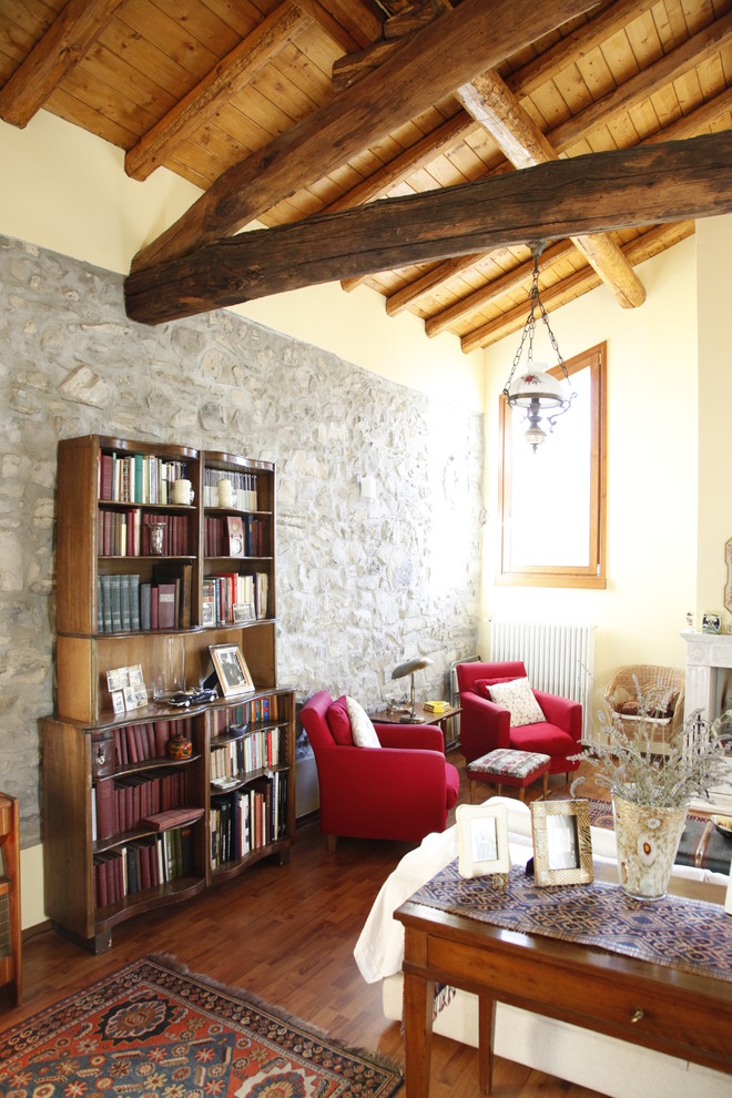 Inspiration pour une salle de séjour chalet de taille moyenne et fermée avec une bibliothèque ou un coin lecture, un mur gris, un sol en bois brun, une cheminée standard et un manteau de cheminée en pierre.