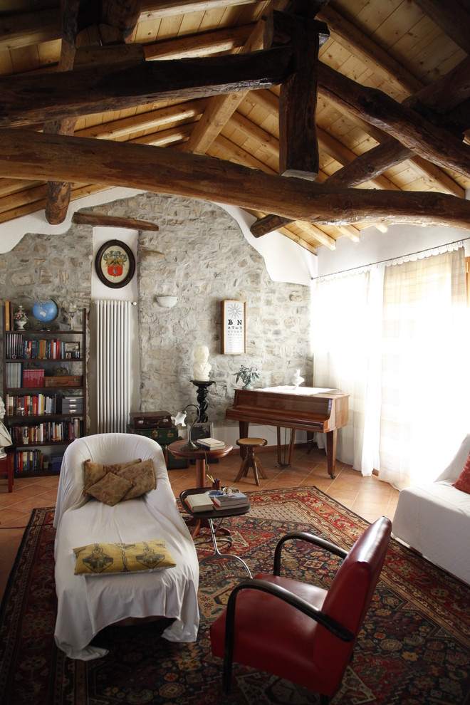 Cette image montre un petit salon chalet ouvert avec un mur gris, une salle de musique, tomettes au sol et un mur en pierre.