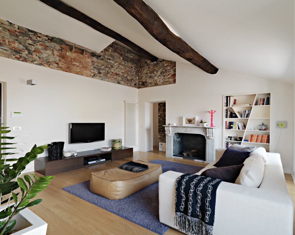 Immagine di un soggiorno design con libreria, pareti bianche, parquet chiaro, camino classico e TV a parete