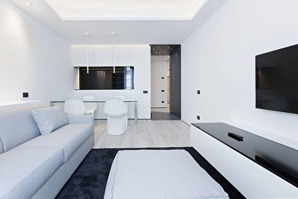 Foto di un soggiorno moderno aperto con pareti bianche, parquet chiaro e TV a parete