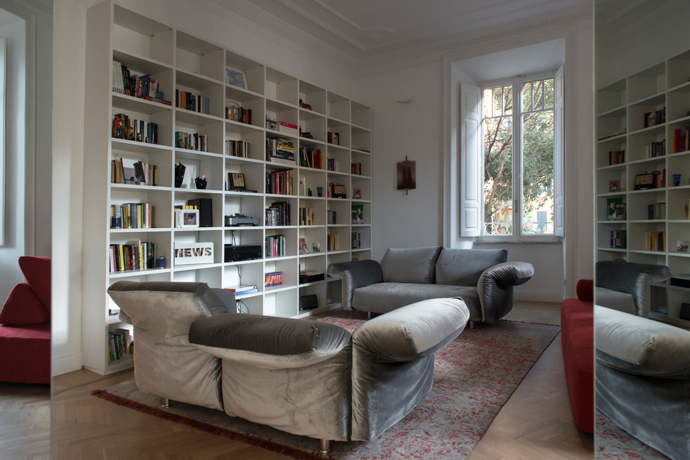 Immagine di un ampio soggiorno contemporaneo aperto con pareti bianche, parquet chiaro e libreria