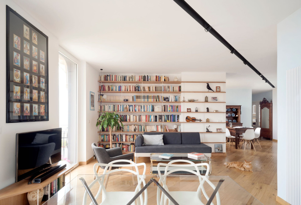 Idee per un grande soggiorno contemporaneo aperto con libreria, pareti bianche, pavimento in legno massello medio e TV a parete