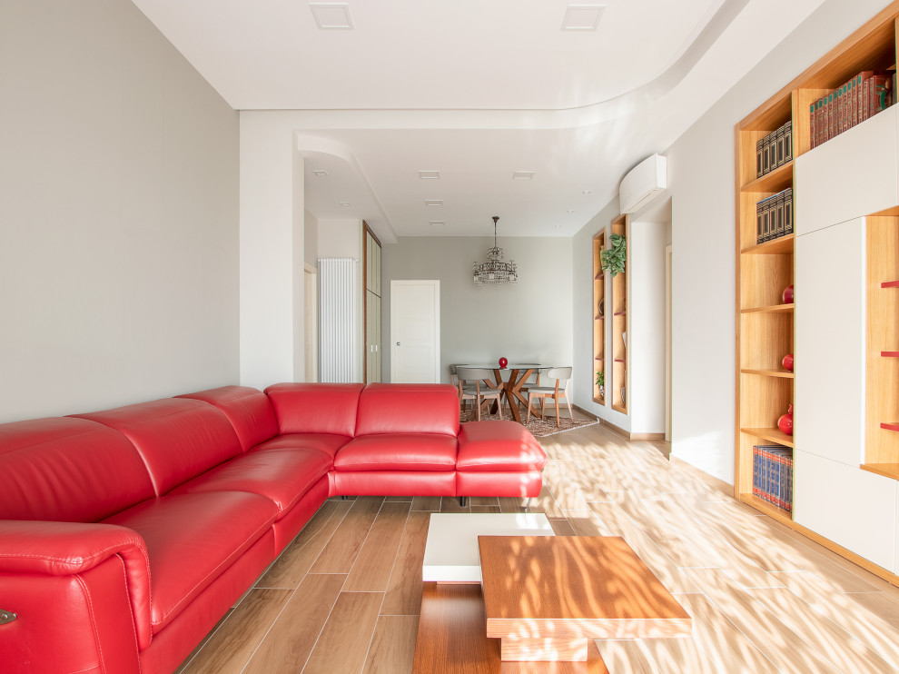 Esempio di un grande soggiorno moderno aperto con libreria, pavimento in gres porcellanato, TV a parete e pareti multicolore