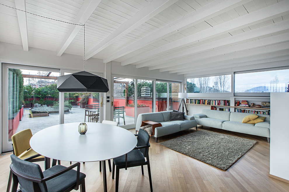 Diseño de salón abierto contemporáneo con paredes blancas y suelo de madera clara