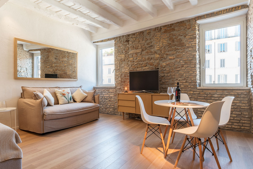 На фото: открытая гостиная комната в средиземноморском стиле с белыми стенами, светлым паркетным полом, бежевым полом, отдельно стоящим телевизором и акцентной стеной без камина с