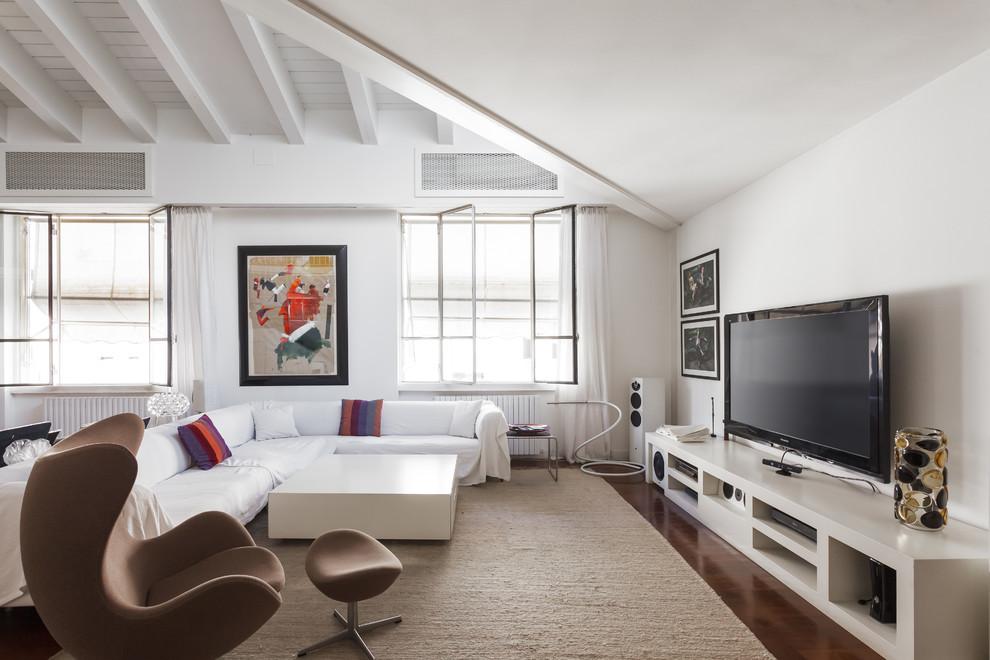 Bild på ett funkis allrum, med vita väggar, mörkt trägolv, en fristående TV och brunt golv