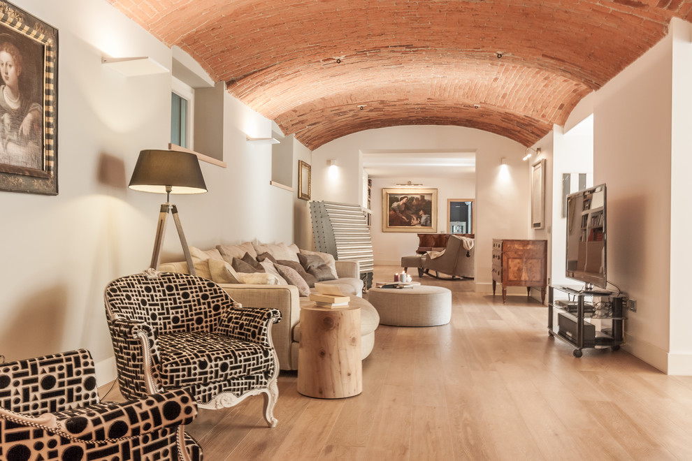 Großes, Offenes Mediterranes Wohnzimmer mit weißer Wandfarbe, hellem Holzboden, freistehendem TV und beigem Boden in Mailand