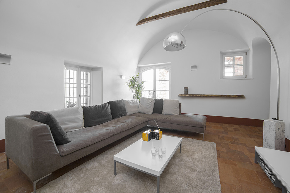 Свежая идея для дизайна: изолированная гостиная комната среднего размера в современном стиле с белыми стенами и кирпичным полом - отличное фото интерьера