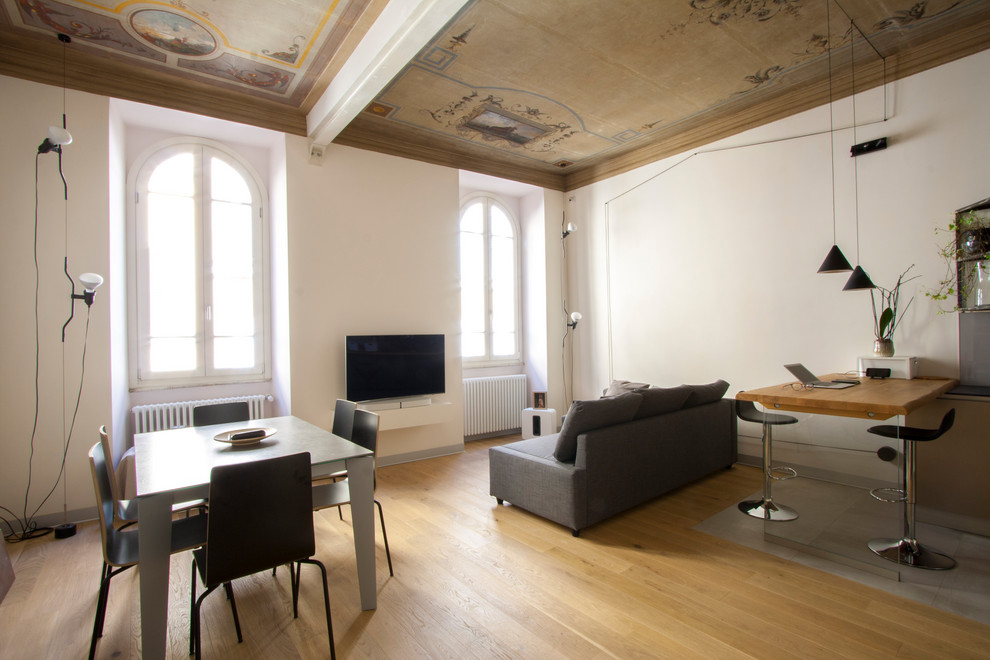 Foto di un grande soggiorno moderno con pareti bianche, parquet chiaro e TV a parete