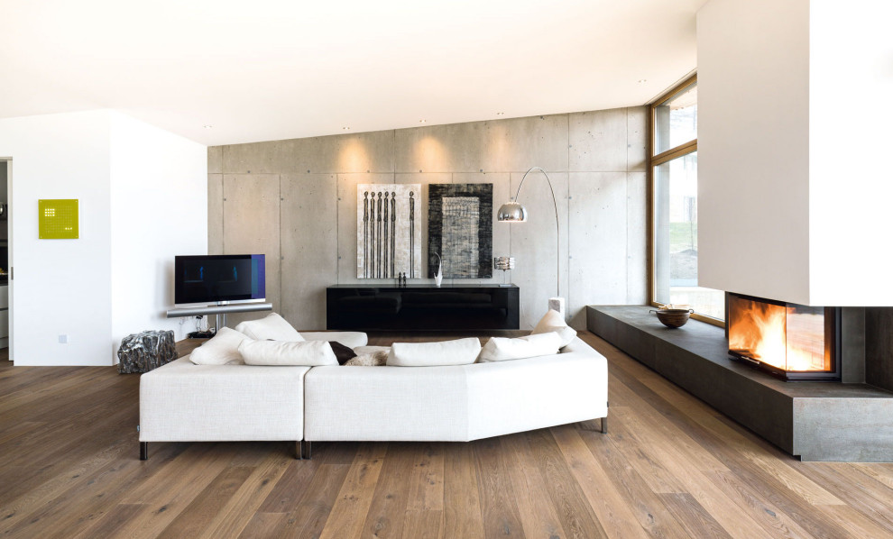 Ejemplo de salón abierto minimalista grande con paredes blancas, suelo de madera clara, todas las chimeneas, marco de chimenea de piedra, televisor en una esquina y suelo marrón