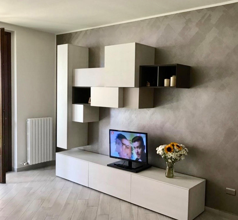 Kleines, Repräsentatives, Offenes Modernes Wohnzimmer mit beiger Wandfarbe, Porzellan-Bodenfliesen und freistehendem TV in Mailand