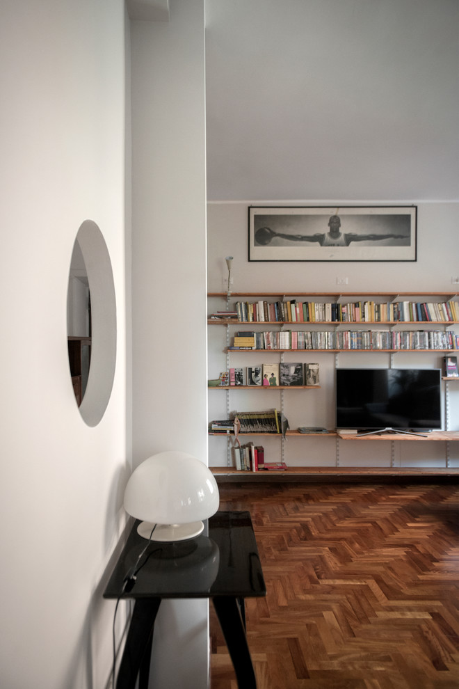 Ejemplo de biblioteca en casa abierta contemporánea de tamaño medio con paredes blancas, suelo de madera oscura y televisor independiente