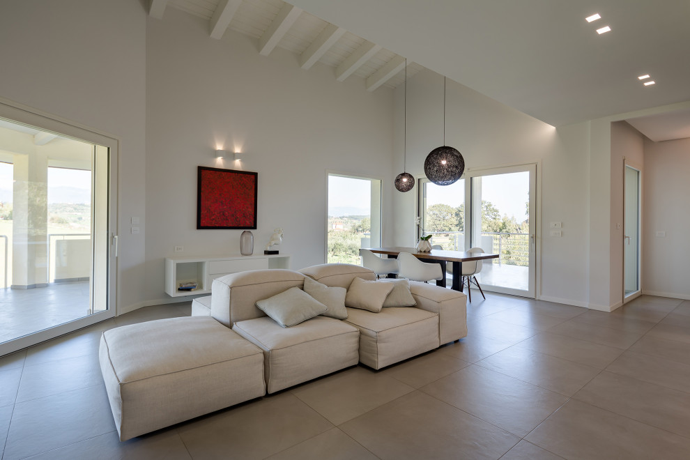 Esempio di un ampio soggiorno design stile loft con pareti bianche, pavimento grigio e travi a vista