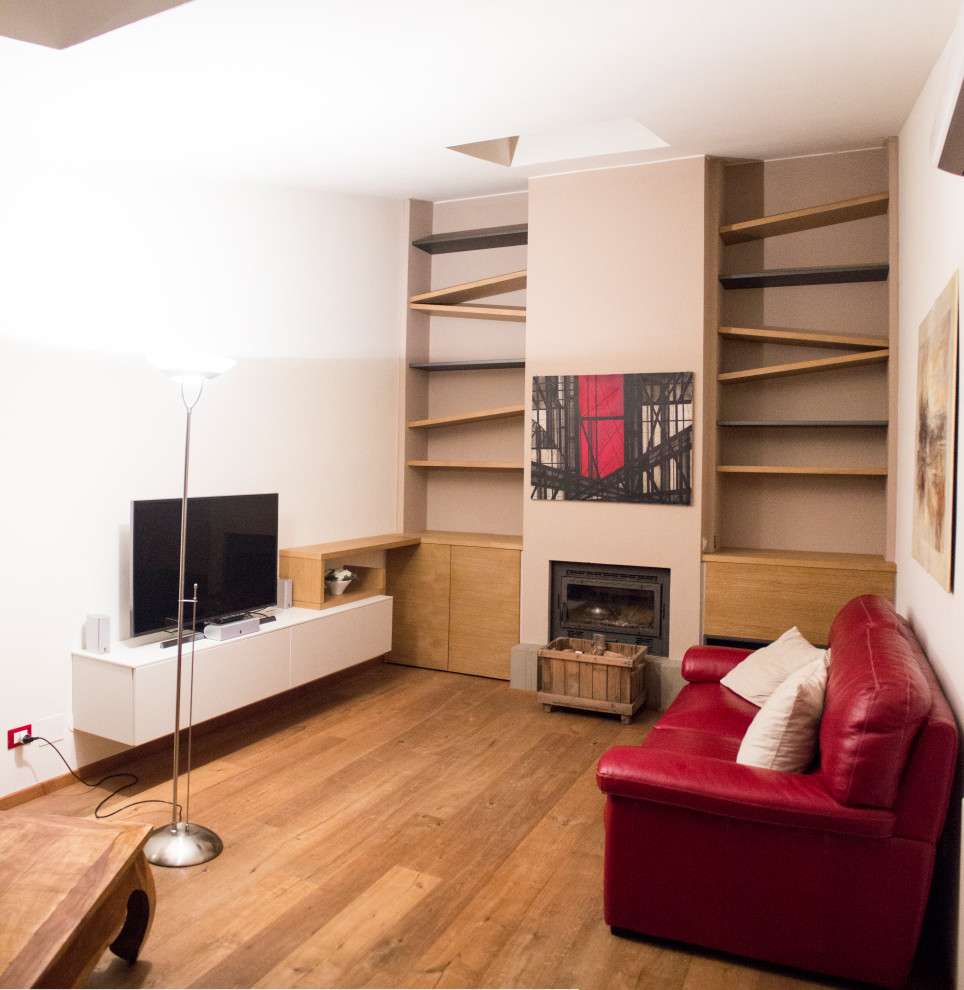 Esempio di un soggiorno minimal di medie dimensioni e aperto con libreria, pareti bianche, pavimento in legno massello medio, stufa a legna e TV a parete